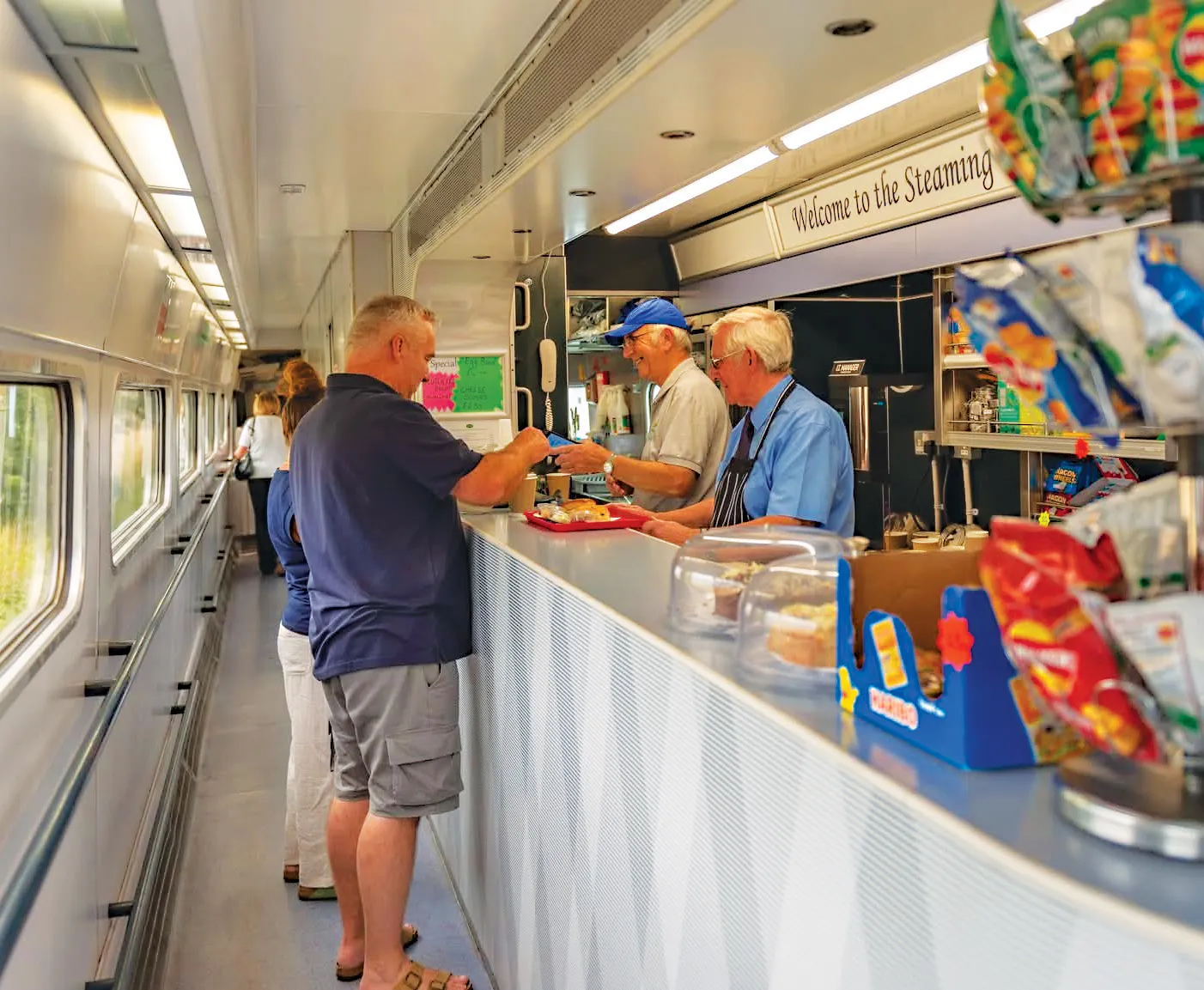Volunteers serving hot drinks and snacks behind the counter of the Steaming Kettle Buffet