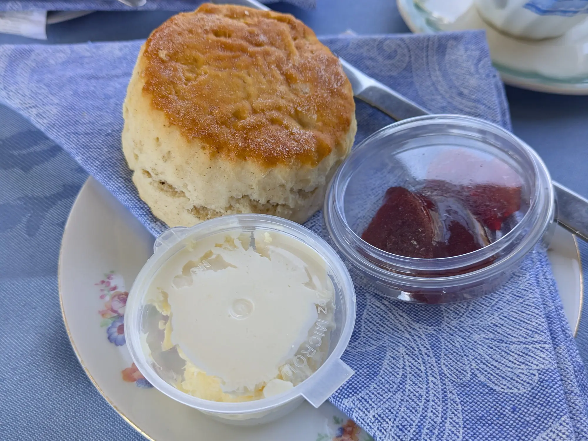 A scone served with pots of cream and jam on a china plate aboard the dining train